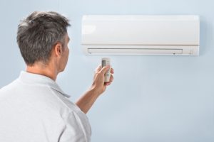 Man Operating Air Conditioner With Remote Controller